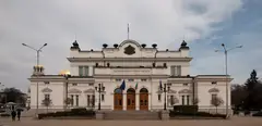 Сградата на Народното събрание в София с надпис „Съединението прави силата“, българско и европейско знаме и куполите на „Св. Александър Невски“ зад нея